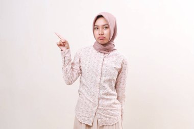 Mutsuz genç Asyalı Müslüman kadın kameraya yan tarafı göstererek bakıyor. Beyazda izole edilmiş