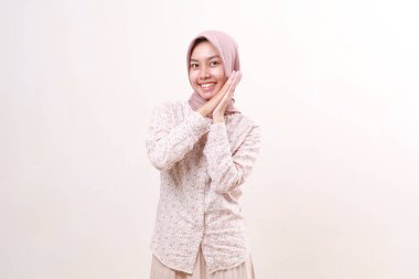 Asyalı neşeli, genç Müslüman kadın. Şaşırmış bir ifadeyle ayakta duruyor. Beyaz arkaplanda izole