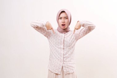 Kızgın mutsuz Asyalı genç müslüman kız başını eğip işaret ediyor. Beyaz arkaplanda izole