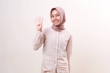 Asyalı genç Müslüman kız dört parmağını gösterirken ayakta duruyor. Beyaz arkaplanda izole