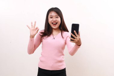 Mutlu genç Asyalı kadın cep telefonu tutarken el hareketi yapıyor. Beyazda izole edilmiş
