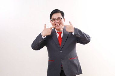 Neşeli heyecanlı Asyalı işadamı gülümsemesini gösterirken ayakta duruyor. Beyazda izole edilmiş