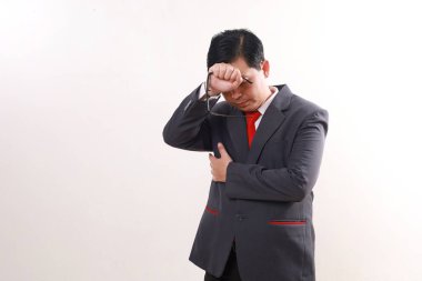 Stresli Asyalı iş adamı başını tutarken ayakta duruyor. Beyaz arkaplanda izole