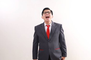 Hayal kırıklığına uğramış Asyalı işadamı çığlık atarken ayakta duruyor. Beyazda izole edilmiş