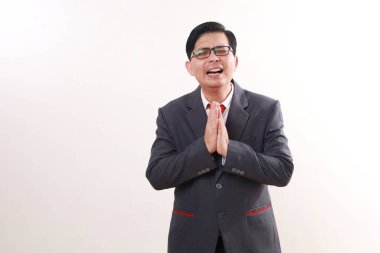 Asyalı işadamı özür dilerken ayakta duruyor. Beyazda izole edilmiş