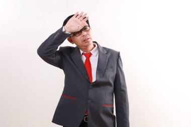 Yorgun Asyalı işadamı başıyla ayakta duruyor. Beyazda izole edilmiş