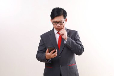 Kafası karışmış Asyalı işadamı bir şey düşünürken elinde cep telefonu tutarken, beyazlar içinde soyutlanmış.