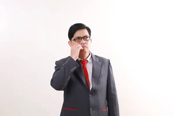 Confused asian businessman standing while thinking an idea and looking at empty space