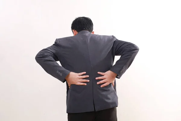 Back view of asian businessman standing while having back pain. Isolated on white