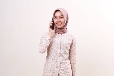 Happy smile young asian muslim girl looking at the camera while on the phone. Isolated on white background