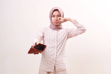 Sad young asian muslim girl standing while showing a empty wallet. Isolated on white