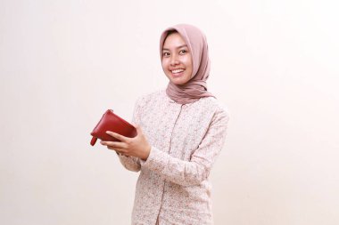 Happy young asian muslim girl standing while holding a wallet. Isolated on white background
