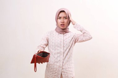 Stressed young asian muslim girl standing while holding a empty wallet. Isolated on white