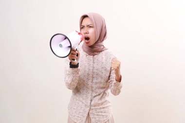 Angry young asian muslim woman shouting or screaming using megaphone. Isolated on white