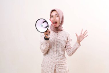 Excited surprised young asian muslim woman shouting using megaphone while looking at the camera