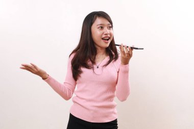 Happy young asian girl standing while using and talking on the phone with loud speaker mode. Isolated on white background