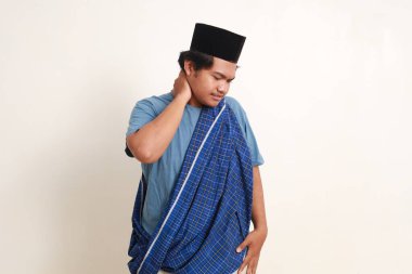 Asyalı genç müslüman çocuğun portresi boynuyla sorun yaşarken ayakta duruyor.