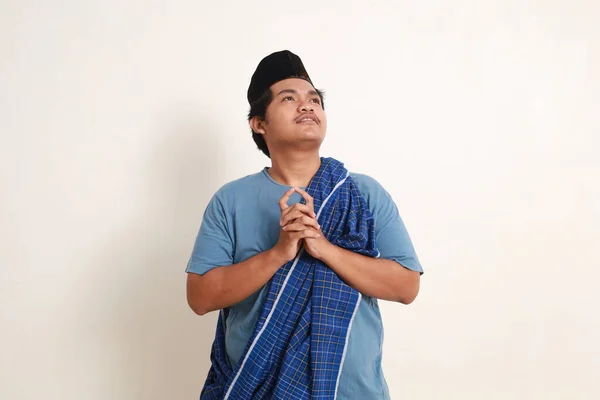Confused young asian muslim boy thinking ideas while looking above
