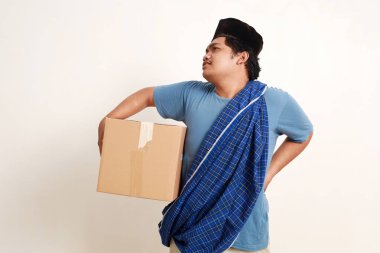 Asyalı müslüman çocuk bir paket taşırken sırtında sorun yaşıyor.