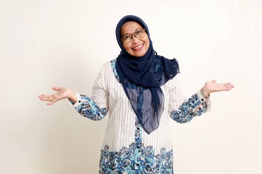 Neşeli Asyalı yaşlı Müslüman kadın gülen surat ifadesiyle ayakta duruyor.