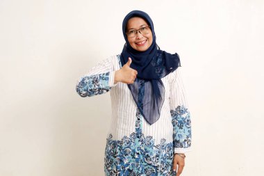 Asyalı yaşlı Müslüman kadın mutlu bir yüz ifadesiyle baş parmak gösteriyor.