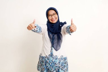 Asyalı yaşlı Müslüman kadın mutlu bir yüz ifadesiyle baş parmak gösteriyor.