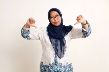 Mutsuz Asyalı yaşlı Müslüman kadın baş parmağını kaldırıyor. El hareketinden nefret ederim.