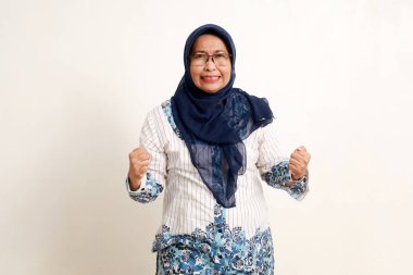 Asyalı yaşlı Müslüman kadın portresi. Kızgın yüz ifadesi ve yumruğu ile ayakta duruyor.