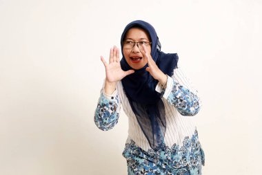 Asyalı yaşlı Müslüman kadın bağırırken ya da yanlardan seslenirken ayakta duruyor