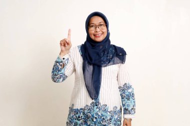 Mutlu Asyalı yaşlı Müslüman kadın parmağını göstererek ayakta duruyor..