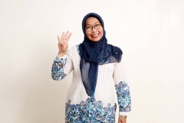 Asyalı yaşlı Müslüman kadın dört parmağını gösterirken ayakta duruyor