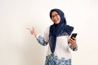Asyalı yaşlı Müslüman kadın cep telefonu tutarken yan tarafı gösteriyor.
