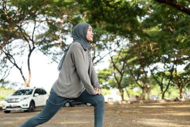 Parkta esneyen Asyalı Müslüman kadın spor kıyafetleri ve başörtüsü