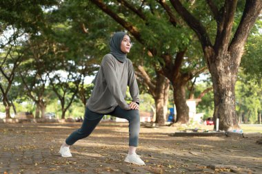 Parkta esneyen Asyalı Müslüman kadın spor kıyafetleri ve başörtüsü