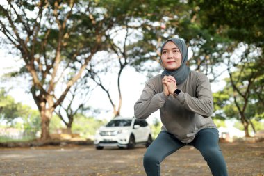 Fit Asyalı Müslüman kadın sabahları dışarıda çömeliyor.