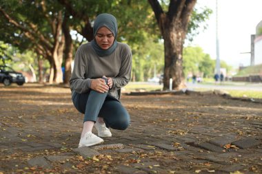 Eklem ağrısı, eklem iltihabı ve tendon sorunları. Asyalı Müslüman bir kadın parkta dizine dokunuyor.