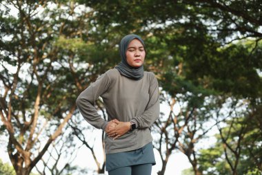 Asyalı peçeli Müslüman kadın sabah dışarıda egzersiz yaparken sağ karnı ağrıyor.