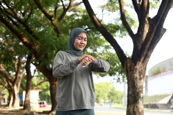 young muslim woman with scarf setting smart watch before jogging in the morning