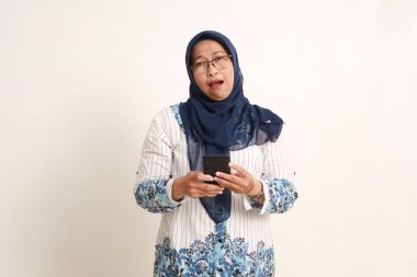 Kameraya bakarken cep telefonu tutan Asyalı yaşlı kadın hayal kırıklığına uğradı.