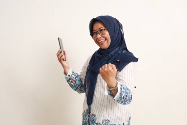 Mutlu Asyalı yaşlı kadın cep telefonunu yumrukla tutarak başarıyı kutluyor.