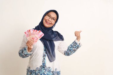 Mutlu Asyalı yaşlı kadın Endonezya banknotlarını tutarken yandan sunum yapıyor.