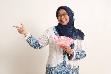 Mutlu Asyalı yaşlı kadın Endonezya banknotlarını tutarken yandan sunum yapıyor.