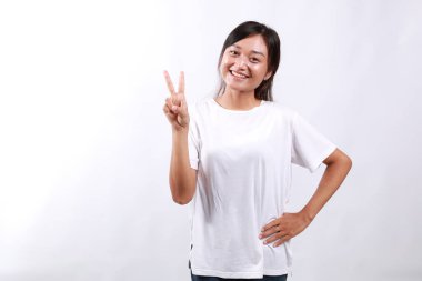 Gülümseyen mutlu Asyalı kız tavsiye veriyor, iki parmağını gösteriyor kuralları açıklarken, işaret ediyor, beyaz arka planda duruyor