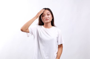 Rahatsız ve yorgun Asyalı bir kadın. Karmaşık görünüyor. Alnına dokunuyor.