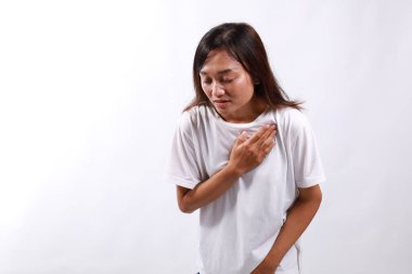 Kalp krizi geçiren, acı çeken, göğsüne dokunup ellerini beyaz arka planda tutan Asyalı hasta bir kadın. İnsan yüzü ifadesi