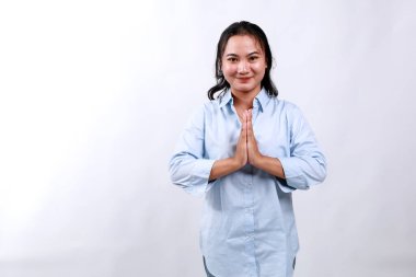 Gülen ve gülümseyen mutlu Asyalı bir kızın görüntüsü. Teşekkür ediyor, namaste jesti, smth için minnettar, beyaz arka planda duruyor.