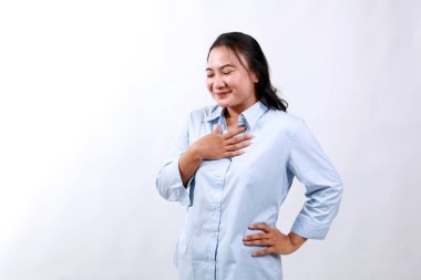 Beyaz stüdyo arka planında izole edilmiş, mutlu, barışçıl Asyalı kadın göğsüne yakın el ele tutuşup gülümseyen, minnettar olan kadın şükranlarını sunar ve sevgisini gösterir.
