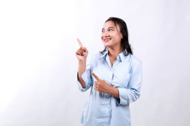 Gülümseyen genç ofis sahibesinin portresi, Asyalı girişimci sol elini göstererek müşteri bilgilerini, fotokopi alanındaki pankart çizelgesini ve beyaz arkaplanı gösteriyor.