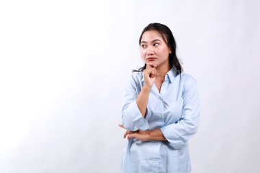 Üzgün, şaşkın ve sıkılmış Asyalı kadın, yalnız ve üzgün bir ifadeyle yan bakıyor, beyaz arka planda duruyor.