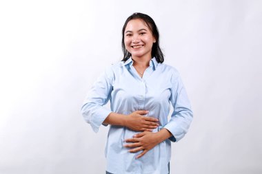 Yemek yedikten sonra karnını ovalayan mutlu Asyalı kadın. Yaşam tarzı, insan duyguları ve güzellik konsepti. Beyazda izole edilmiş